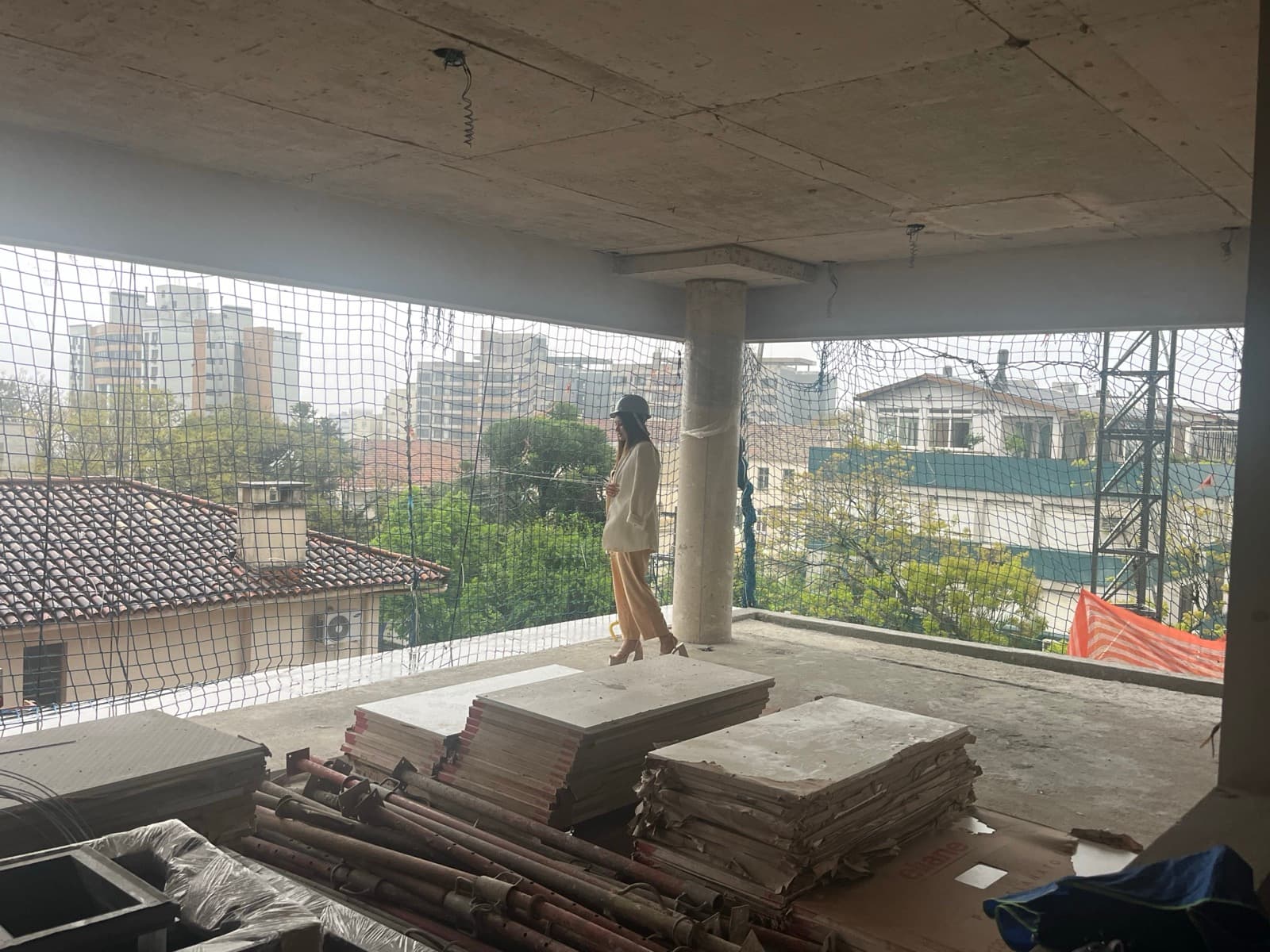 A concrete slab on site, with the architect in a hard hat by the safety netting